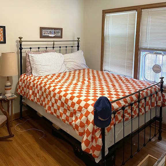 a bed with a red and white checkered comforter and a blue cap on it.