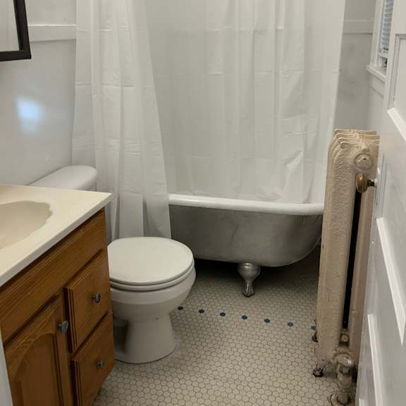 a white toilet sits next to a white shower curtain in a bathroom.