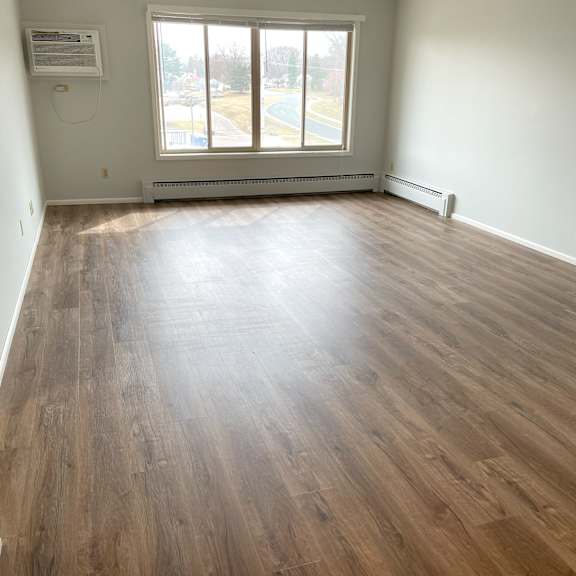 graciously-sized, sunlit living room with large picture window.