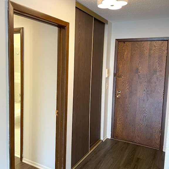 a hallway with a brown door and a mirror on the wall.