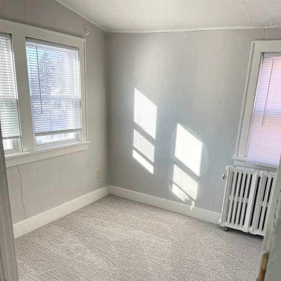 a room with a carpeted floor and a window with blinds.