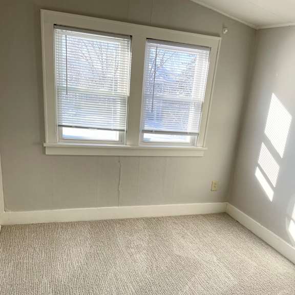 a room with a carpeted floor and two windows.