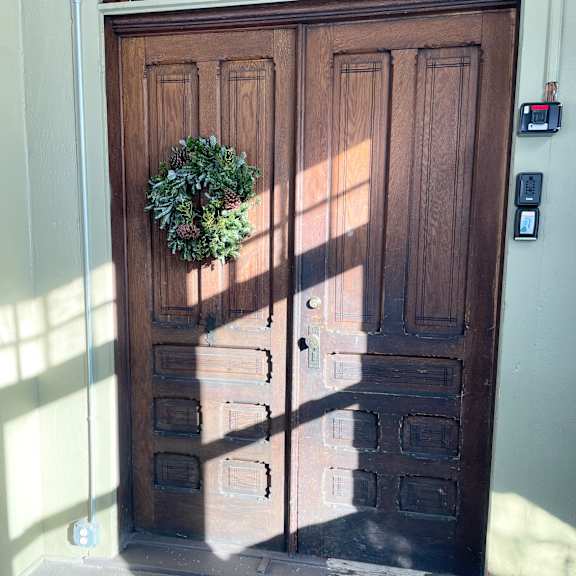 a brown wooden door with a wreath on it.