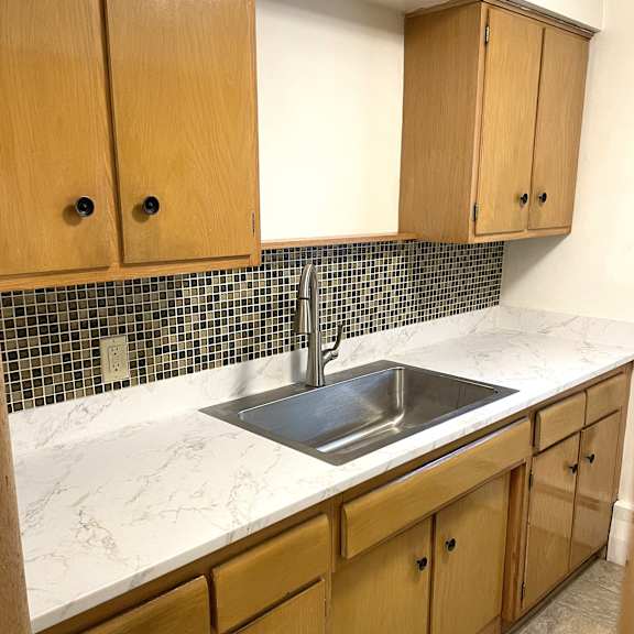 upgraded kitchen with new countertops, sink, faucet, and attractive mosaic tiled backsplash.
