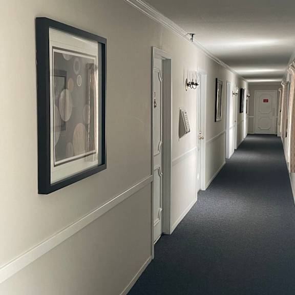 a long hallway with doors on both sides and pictures on the wall.