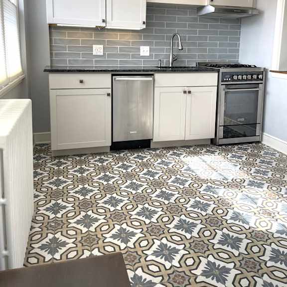 a kitchen with a patterned floor and white cabinets.