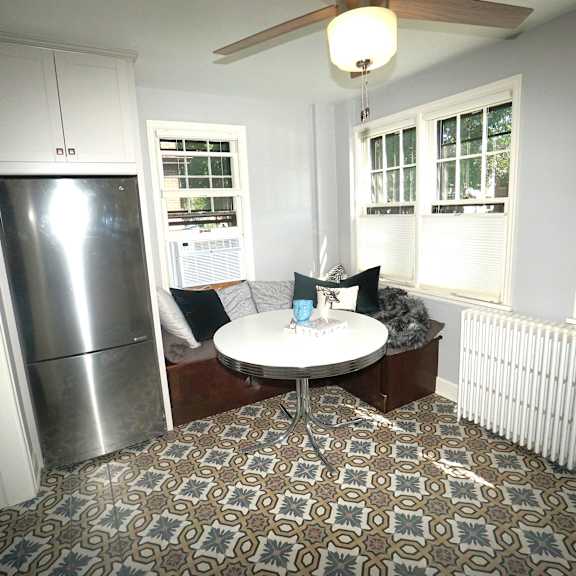 a kitchen with a refrigerator and a dining table with chairs.