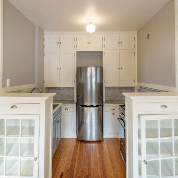 a kitchen with white cabinets and a stainless steel refrigerator.