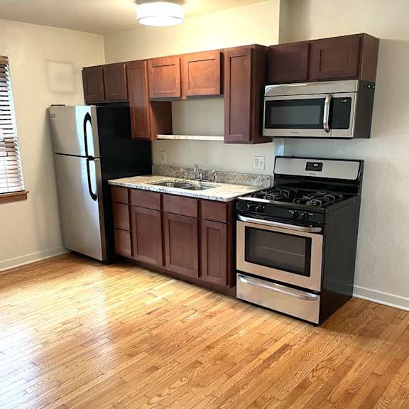 a kitchen with wooden floors and brown cabinets.