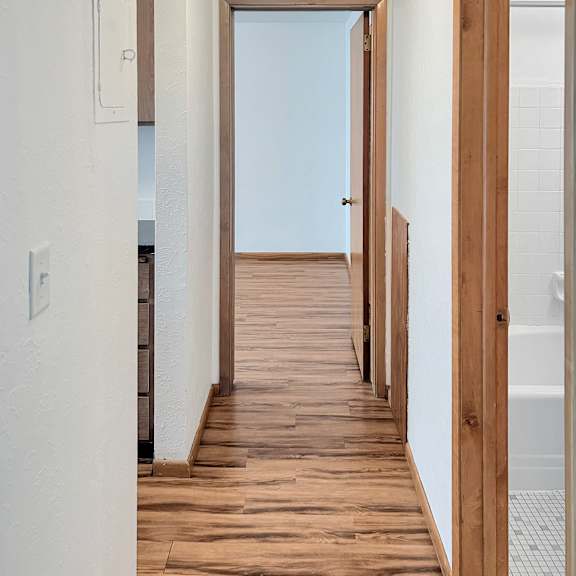 a long hallway with wood floors and white walls.