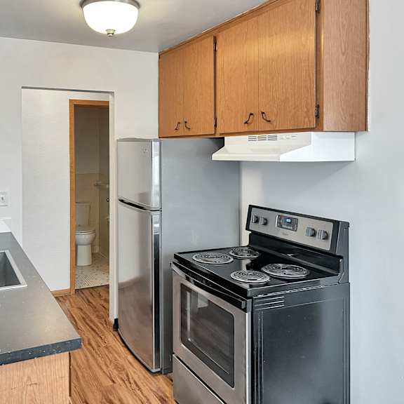 a kitchen with a stove, sink, and cabinets.