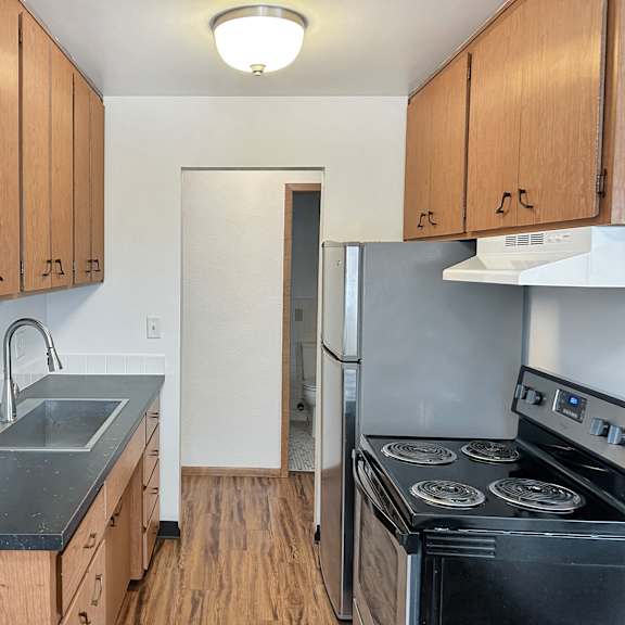 a kitchen with wooden cabinets and a black countertop.