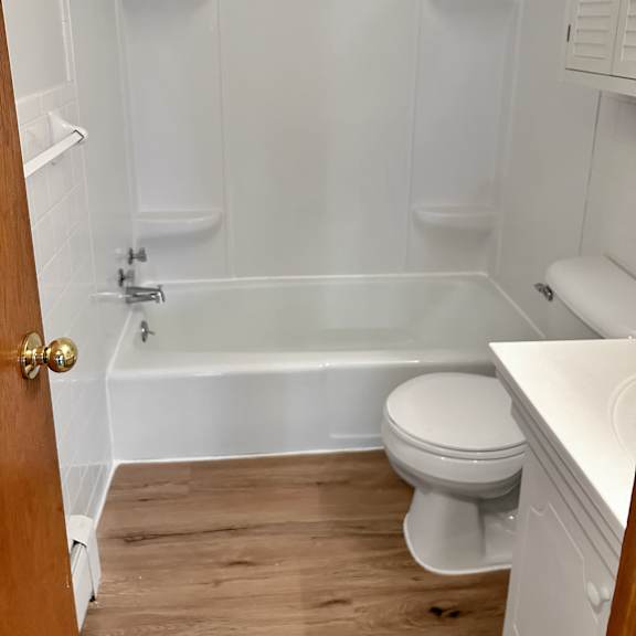 a white toilet sits in a white bathroom with a white tub and a white sink.