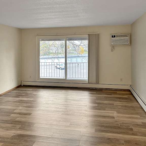 a room with wooden flooring and a window with blinds.