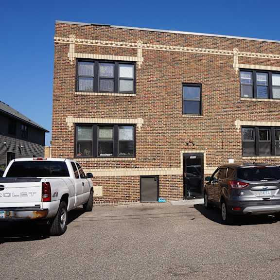 a white pickup truck is parked in front of a brick building.