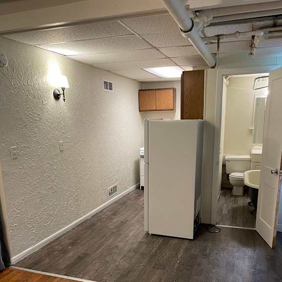 a white refrigerator in a room with wooden floors and a white wall.