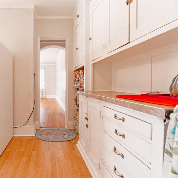 a white refrigerator in a kitchen with wooden floors and white cabinets.