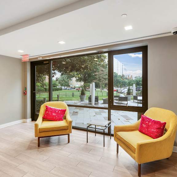 two yellow chairs with red pillows in clubroom at the graham at southern towers, alexandria, 22311