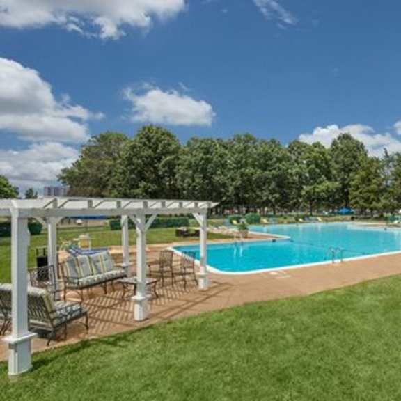 a pool surrounded by a grassy area and trees.at sherwood at southern towers, alexandria virginia
