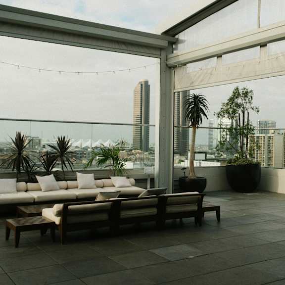 a rooftop patio with a couch, chairs, and a view of the city.