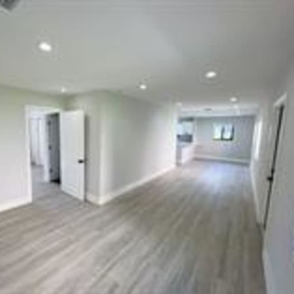 a long empty room with wooden floors and white walls.