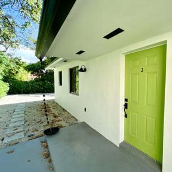 a green door is on the side of a white building.