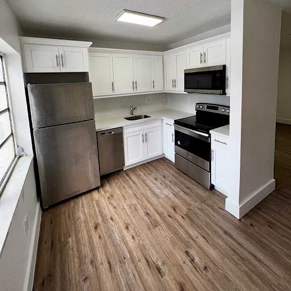 a kitchen with white cabinets and a wooden floor.