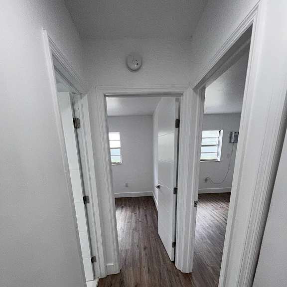 a long hallway with white walls and wood floors.