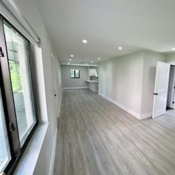a long, empty room with wood flooring and white walls.