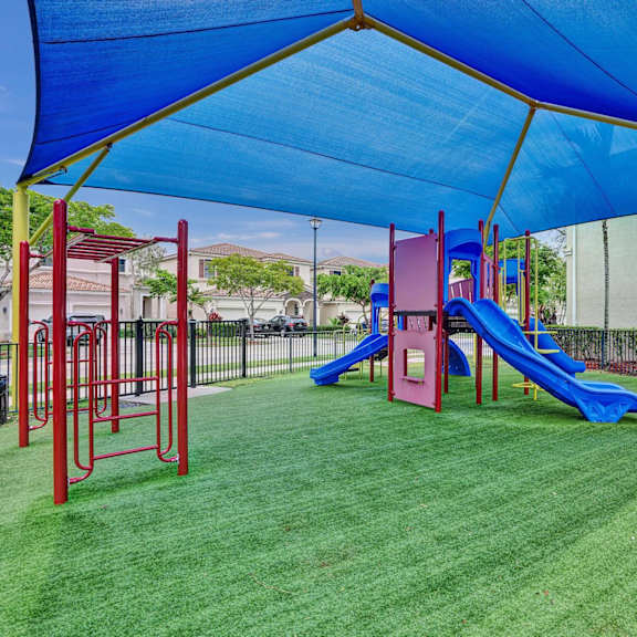 gate enclosed, covered playground with a blue slide and a green canopy.