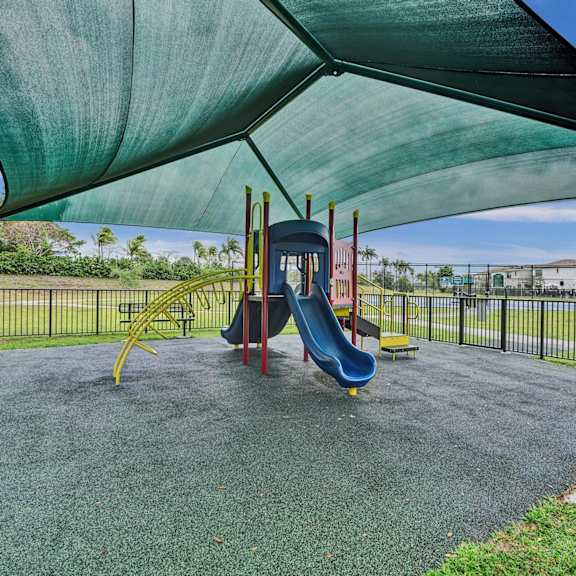 gate enclosed, covered playground with a blue slide and a green canopy.