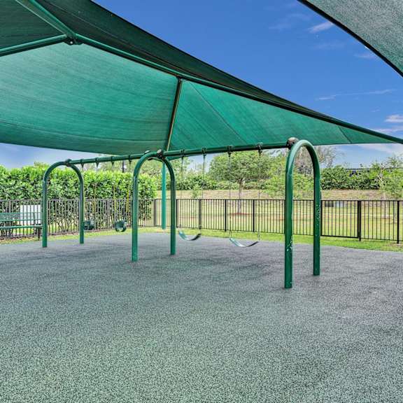gate enclosed, covered playground with swings.