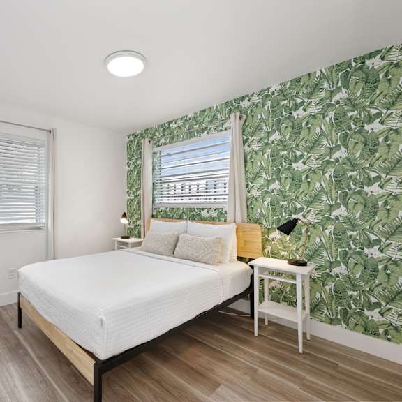 a bedroom with a bed, nightstand, and a wallpapered wall.