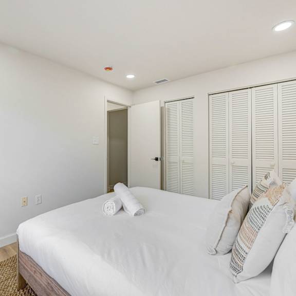 a bedroom with a bed, pillows, and a lamp.