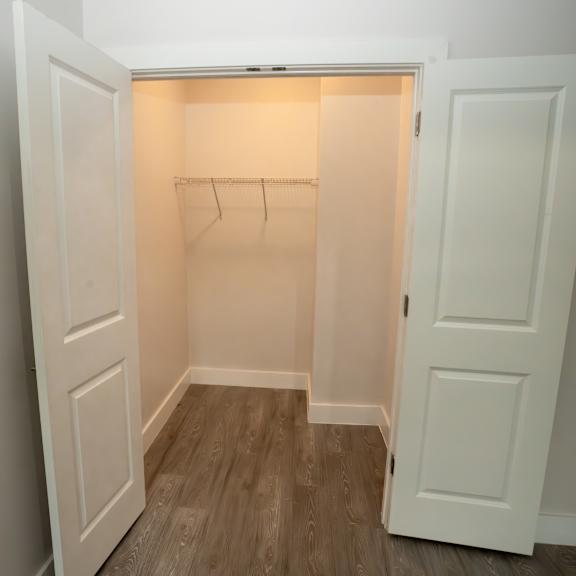 a white closet with a wooden floor and a white door.