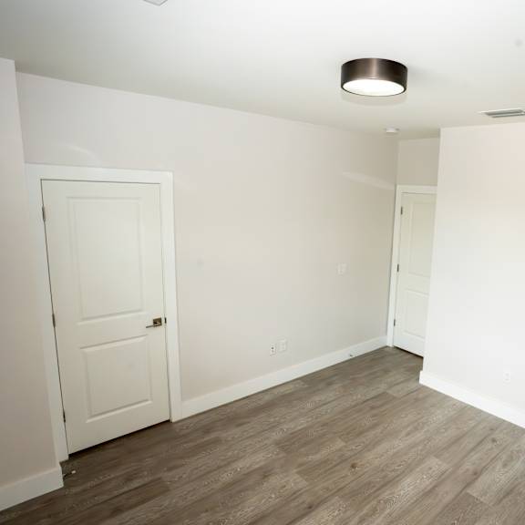 a room with a white door and a wooden floor.