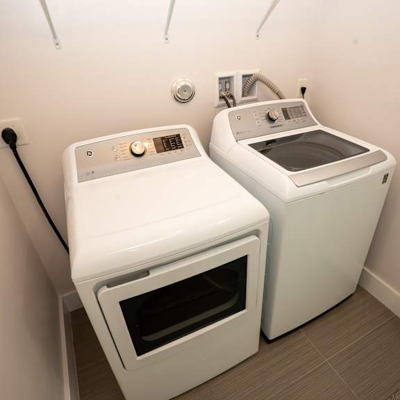 two white front loading washing machines in a small laundry room.
