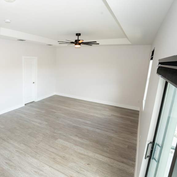 a room with a ceiling fan and wooden flooring.