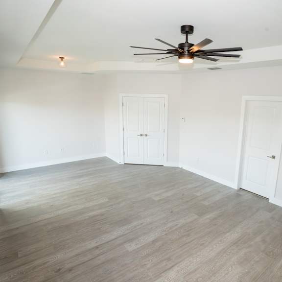 a room with a ceiling fan and wooden flooring.