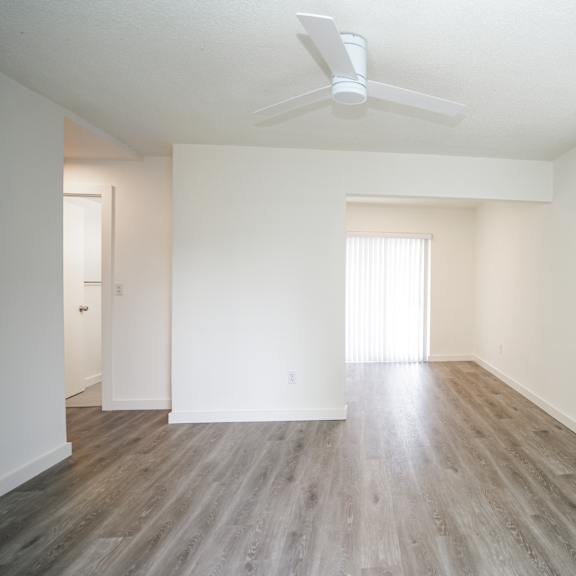 a room with a ceiling fan and wooden flooring.