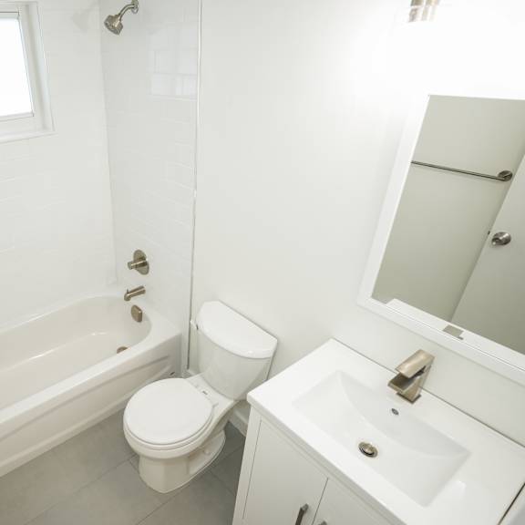 a white bathroom with a toilet, sink, and bathtub.