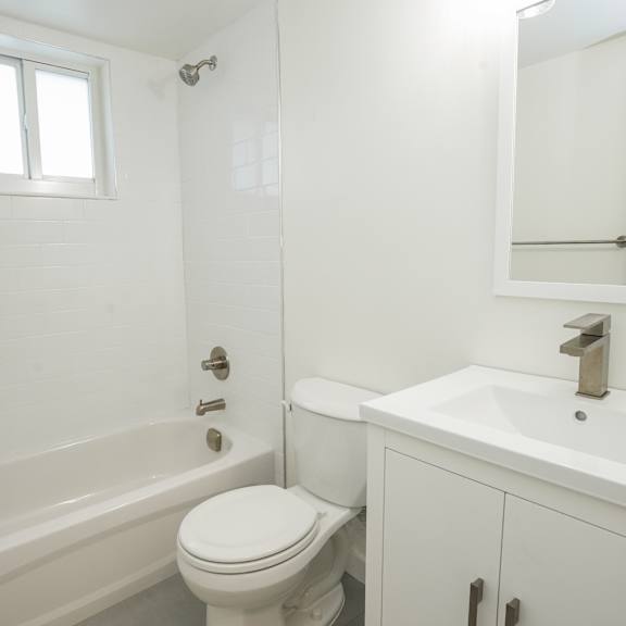 a white bathroom with a toilet, sink, and bathtub.