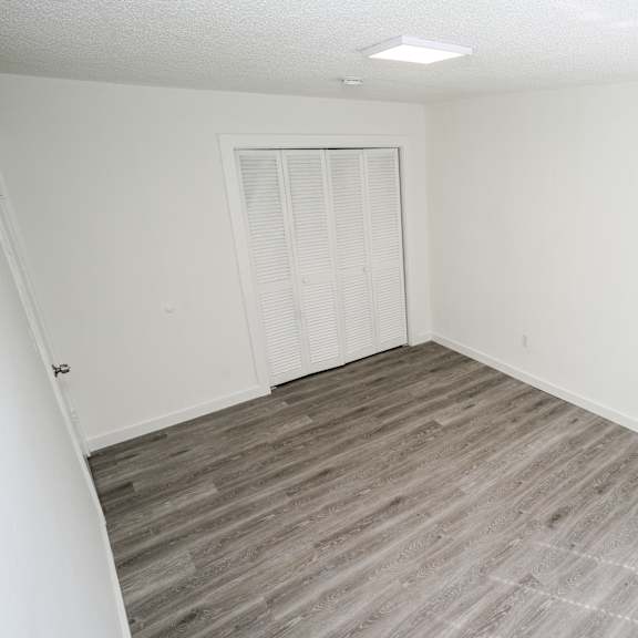 a room with a white door and wooden flooring.