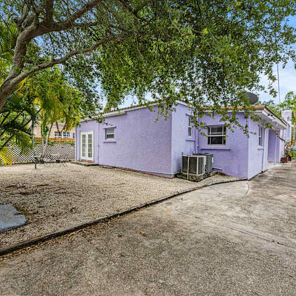 a purple house with a white fence and a tree in front.