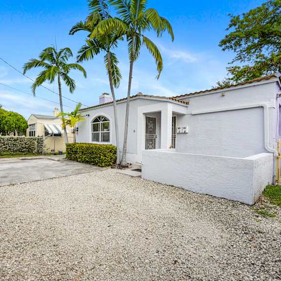 a white house with a gravel driveway and a gate.