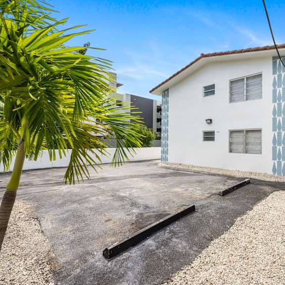 a white house with a blue patterned wall is surrounded by palm trees.