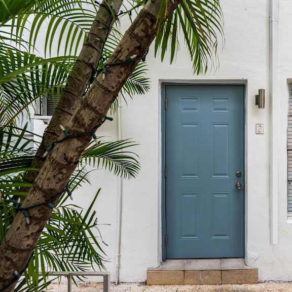 a blue door is on the left side of a white building.