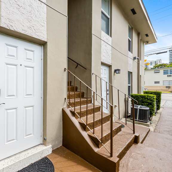 a white door with a black handle is on the left side of a staircase.