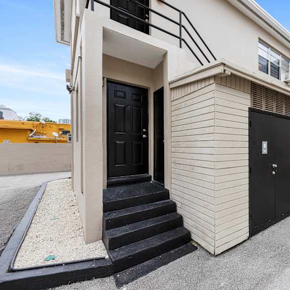 a building with a black door and steps leading up to it.