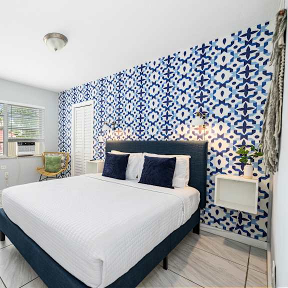 a bedroom with a bed, a window, and a wallpapered wall.